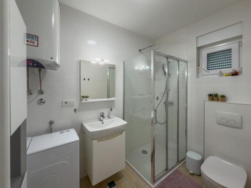 a white bathroom with a shower and a sink at Enamare mit Terrasse in Šimuni