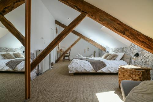 two beds in a attic bedroom with wooden beams at Maison du Bonheur, Gîtes in Le Pin