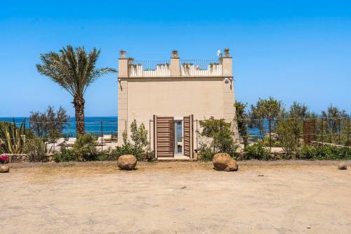 a small house with a fence and a palm tree at Torre dei 7 Frati in Cefalù