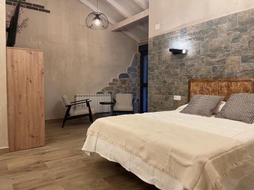 a bedroom with a large bed and a stone wall at Casa Los Tres Panetes Béjar in Béjar