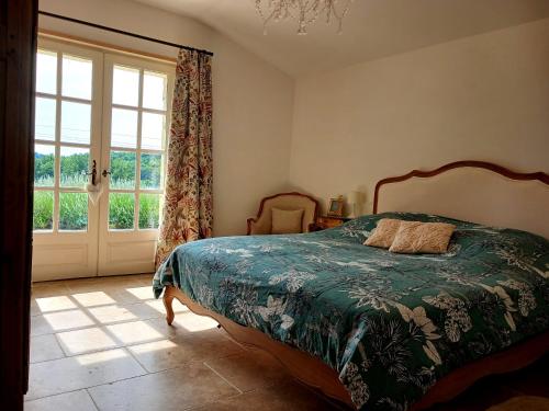 a bedroom with a bed and a large window at Les Volets Verts-Dordogne in Plazac