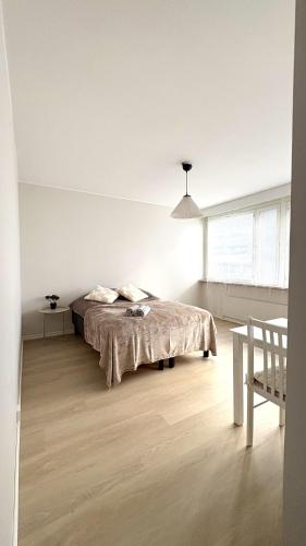 a white bedroom with a bed and a table at City Studio Kalliossa in Helsinki
