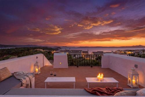 a sunset from a balcony with tables and candles at Porto Cervo Cala Del Faro, Villetta con Giardino e Rooftop in Cala Del Faro