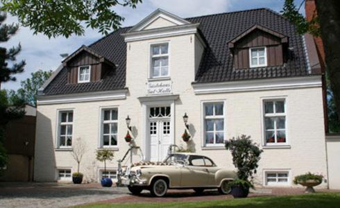 an old car parked in front of a white house at Landhaus Gut Halte in Papenburg