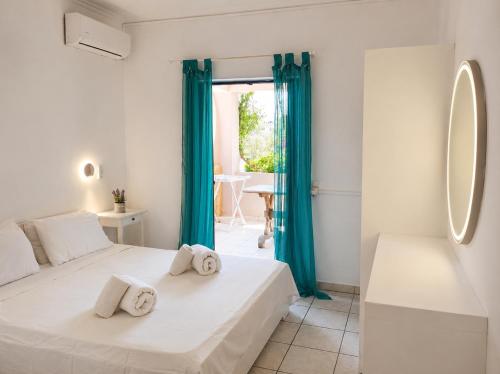 a white bedroom with blue curtains and a bed at Votsalon Beach House - 30 meters from Alykes Beach in Katastárion