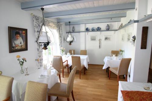 a dining room with white tables and chairs at Landhaus Gut Halte in Papenburg