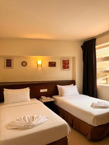 a hotel room with two beds and a window at New century inn in Bintulu