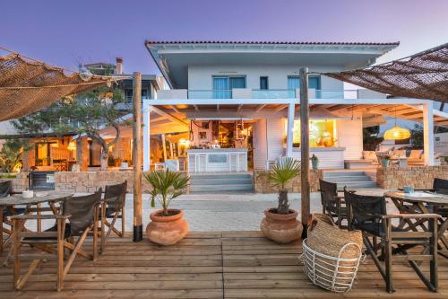 a patio with tables and chairs and a house at Adriana beach in Pefkochori