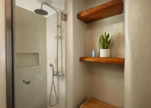 a bathroom with a shower with a glass door at Falcon Eyes- Panoramic stone house in Andros