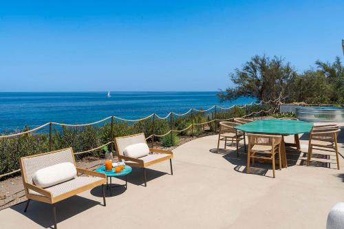 a patio with a table and chairs and the ocean at Torre dei 7 Frati in Cefalù