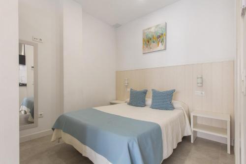 a white bedroom with a bed with blue pillows at Modern Loft in Málaga in Málaga