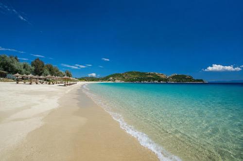 a beach with chairs and umbrellas and the ocean at Votsalon Beach House - 30 meters from Alykes Beach in Katastárion