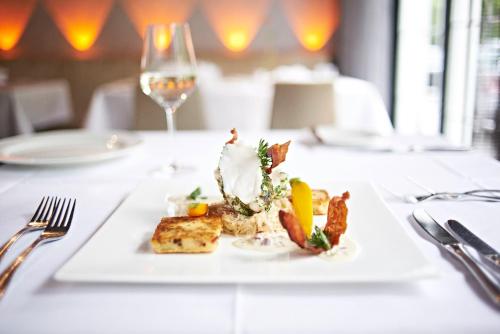a plate of food on a table with a glass of wine at Hotel Zugbrücke Grenzau GmbH in Höhr-Grenzhausen
