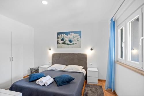 a bedroom with a bed with blue sheets and pillows at Apartment & Rooms - Marina in Ploče