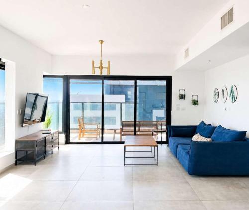 a living room with a blue couch and a tv at Magical 4BR APT With Panoramic Sea View l Mamad in Bat Yam