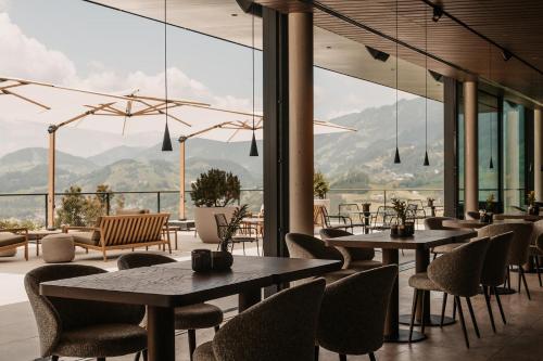 a restaurant with tables and chairs and mountains in the background at Hotel Oberforsthof in Sankt Johann im Pongau