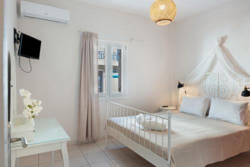 a white bedroom with a bed and a window at Driopida 5 Irida Kythnos in Mérikhas