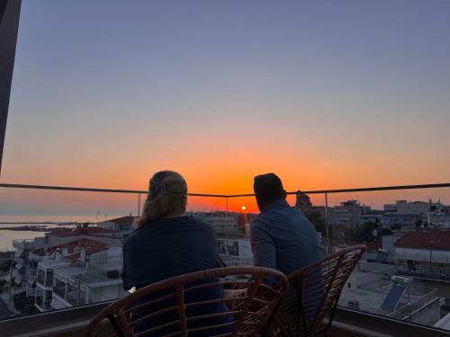 two people sitting on a balcony watching the sunset at Petra Mare - Sea View Escape in Nea Moudania in Nea Moudania