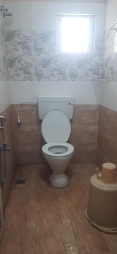 a bathroom with a white toilet and a window at SRM Residency in Alāndurai