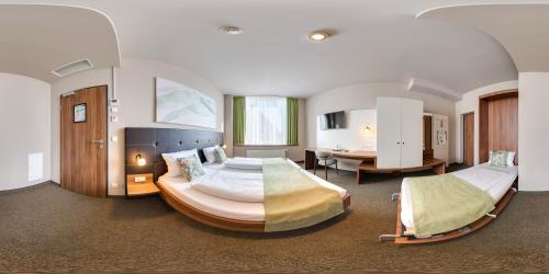 a large bedroom with two beds and a desk at JOESEPP´S HOTEL am Schweizerberg in Memmingen