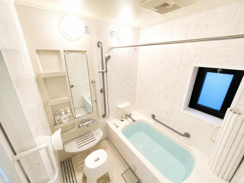 a bathroom with a tub and a toilet and a television at West Press Sasebo in Sasebo
