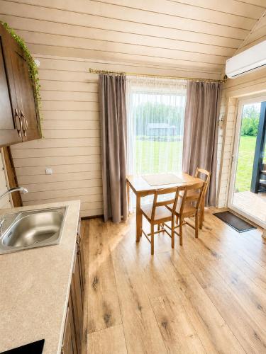 a kitchen with a table and chairs in a room at Atpūtas mājas Leiksnīte in Vaikulāni
