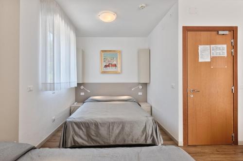a small room with a bed and a door at Hotel Meublè Zenith in Lignano Sabbiadoro