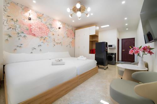 a bedroom with a large white bed with flowers on the wall at The Pivot Suite Ben Thanh - District 1 in Ho Chi Minh City