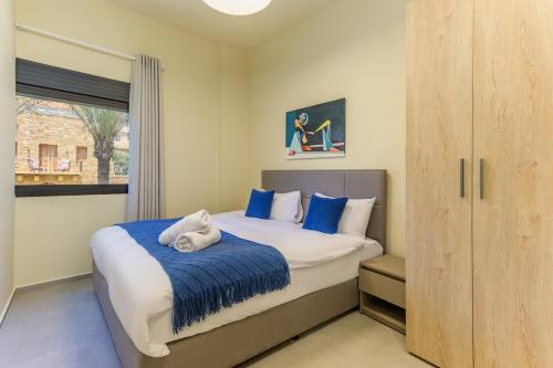 a bedroom with a bed with blue sheets and a window at Capri 2-BR Apartment In Bahsa Batroun in Batroûn