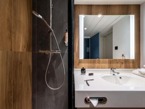 a bathroom with a shower and a sink and a mirror at Mercure Grenoble Centre Alpotel in Grenoble