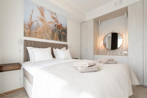a white bedroom with a large bed with towels on it at Marienholm Seaview Apartment in Haapsalu