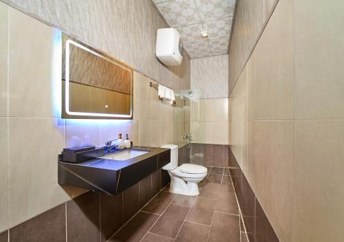 a bathroom with a toilet and a sink and a mirror at Eluna Lilly Da Lat Hotel in Da Lat