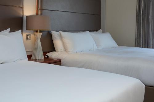 a hotel room with two beds and a lamp at Cheltenham Chase Hotel & Spa in Cheltenham
