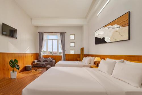 a bedroom with a large white bed and a couch at Eluna Lilly Da Lat Hotel in Da Lat