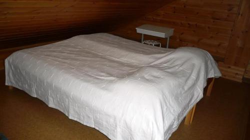 a bedroom with a white bed with a wooden wall at Lomaniini in Tahkovuori