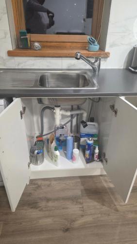 a sink under a kitchen counter with food and drinks at Castle Studio Apartment in Dunedin