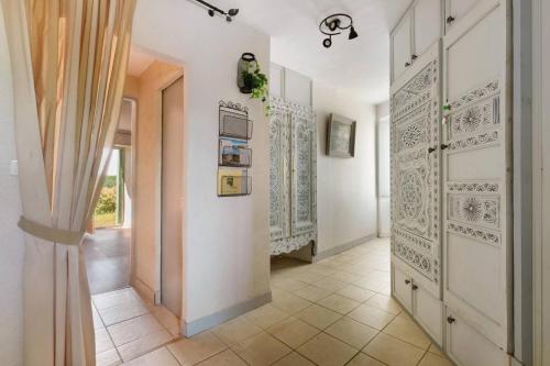 a hallway with white walls and a door with a curtain at Le Logis des Douves in Tiffauges