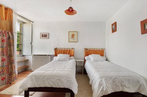 two beds in a room with a window at Le Logis des Douves in Tiffauges