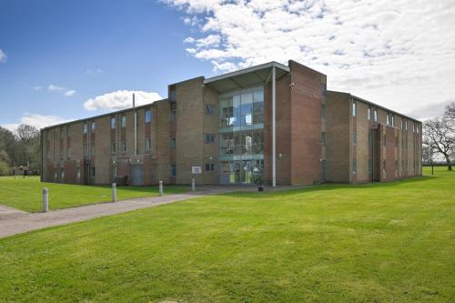 a brick building with a grass field in front of it at Fire Service College in Moreton in Marsh