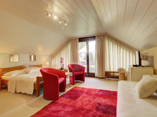 a bedroom with a bed and two red chairs at Apartments Dolžan in Bled