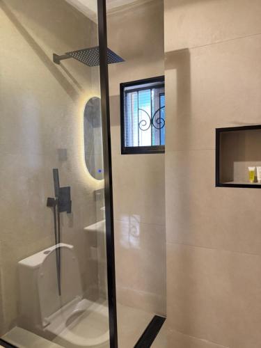 a bathroom with a shower and a toilet and a window at Roseann Gold Boutique Hotel in Kusafe