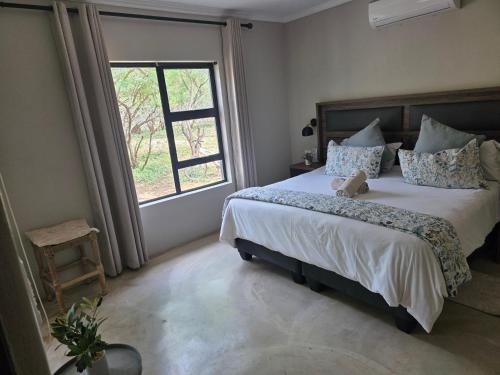 a bedroom with a large bed and a window at Taíta Lodge in Marloth Park