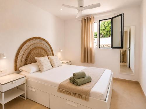a white bedroom with a large bed and a window at Hermosa casa con piscina cerca de la playa de Punta Prima in Punta Prima