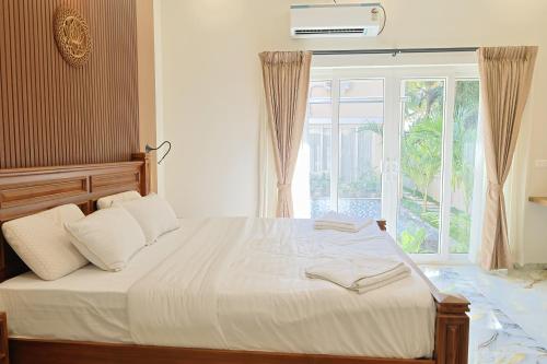 a bedroom with a bed with a large window at MHOMES Resort - Madurai in Alagar Kovil