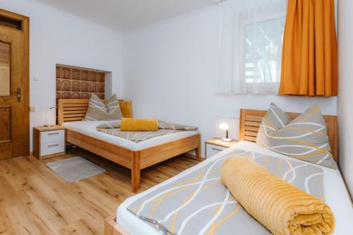 a bedroom with two beds and an orange curtain at Appartement Lackner TOP 2 - Weissensee in Weissensee
