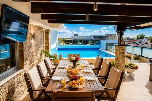 a table on a balcony with a view of a pool at Luxury Penthouse with private pool in Preveza