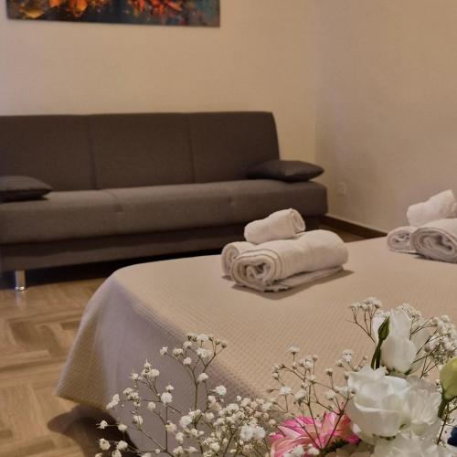 a living room with two beds with towels and a couch at Maresia Apartment in Altavilla Milicia