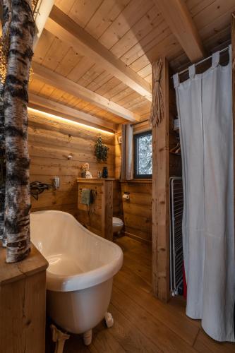 a bathroom with a white bath tub in a log cabin at Lodge 3 - LE JOLIS CHALETS in Barbey-Séroux