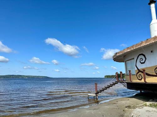a lighthouse with people standing on a dock next to the water at Secret River Rooms in Pereiaslav-Khmelnytskyi