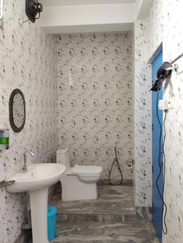 a bathroom with a white sink and a toilet at Relax Hotel in Bāghdogra